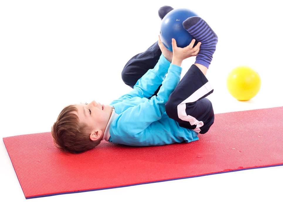 Ergotherapie Vaihingen: Pädiatrie. Kind auf Gymnastikmatte bei Übung mit Gymnastikball